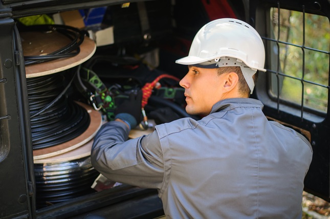 Worker with spool of fiber-optic cable getting ready for installment